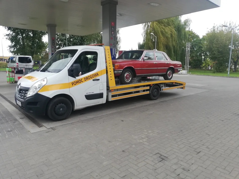 Czerwony klasyczny sedan przewożony na białej lawecie